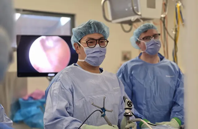 Dr. John Choi holding an endoscope and an optical navigation tracker during endoscopic spine surgery