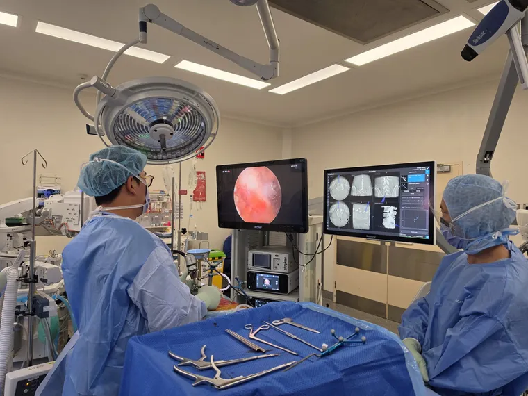 Operating theatre with a 4K endoscopy screen and a spinal navigation display used side by side during minimally invasive spine surgery